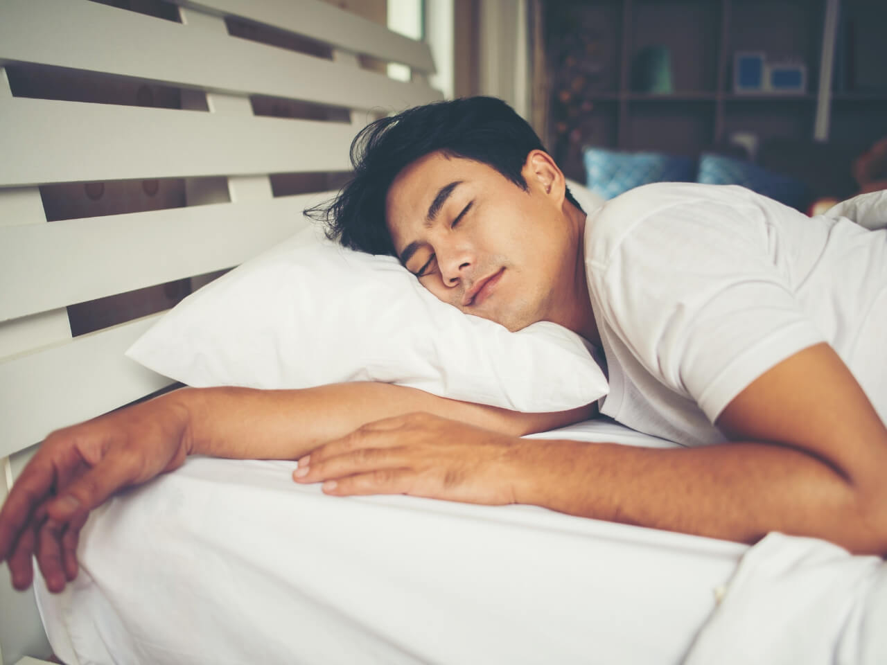 ベッドでうつ伏せで熟睡する男性